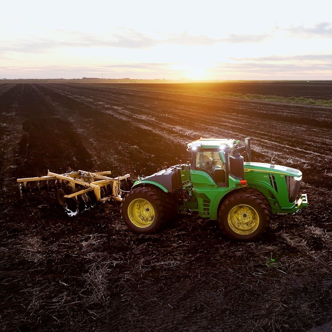 John Deere tractor with a cultivation implement in a South Florida field at sunset