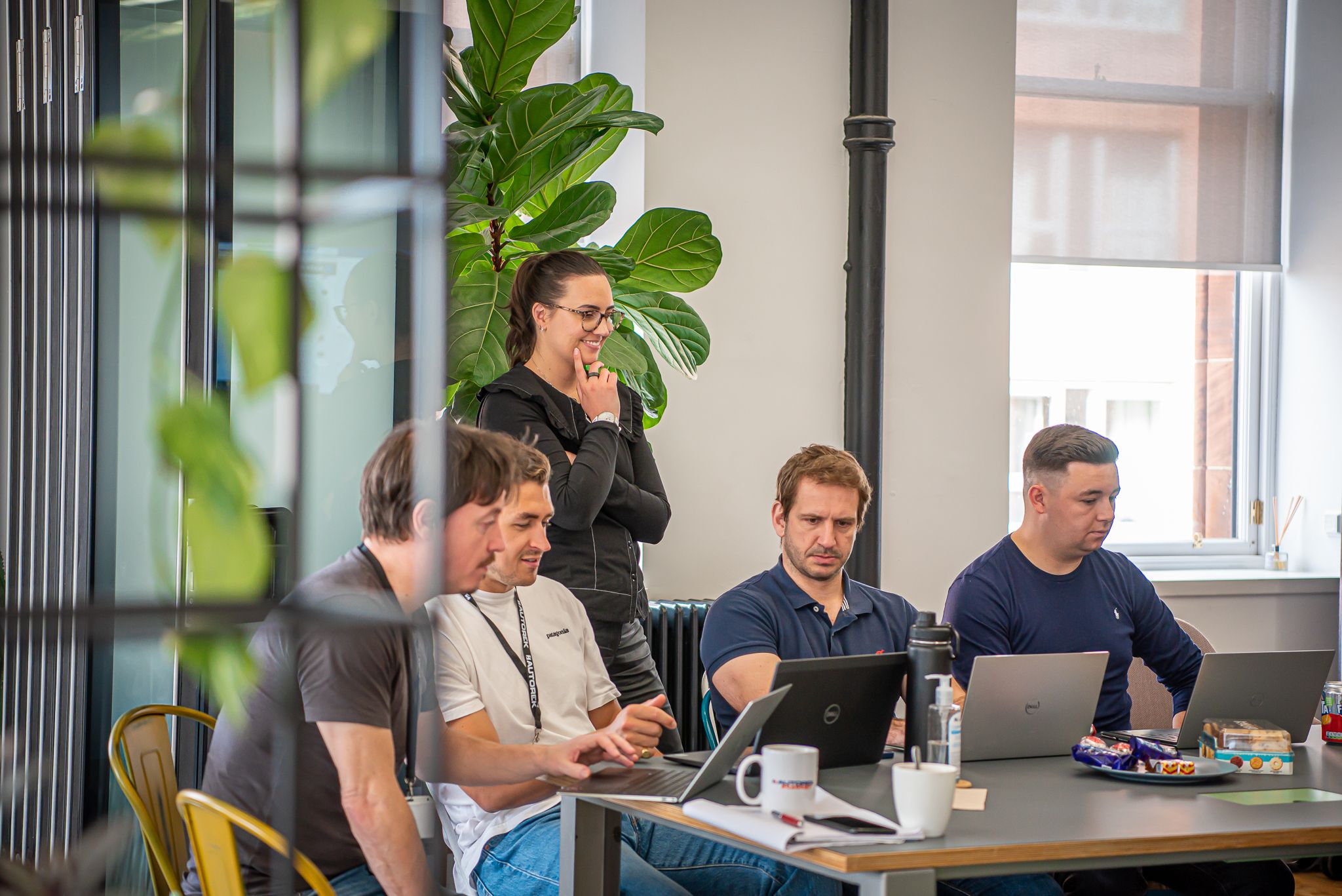 AutoRek colleagues gathered around laptops at an office table