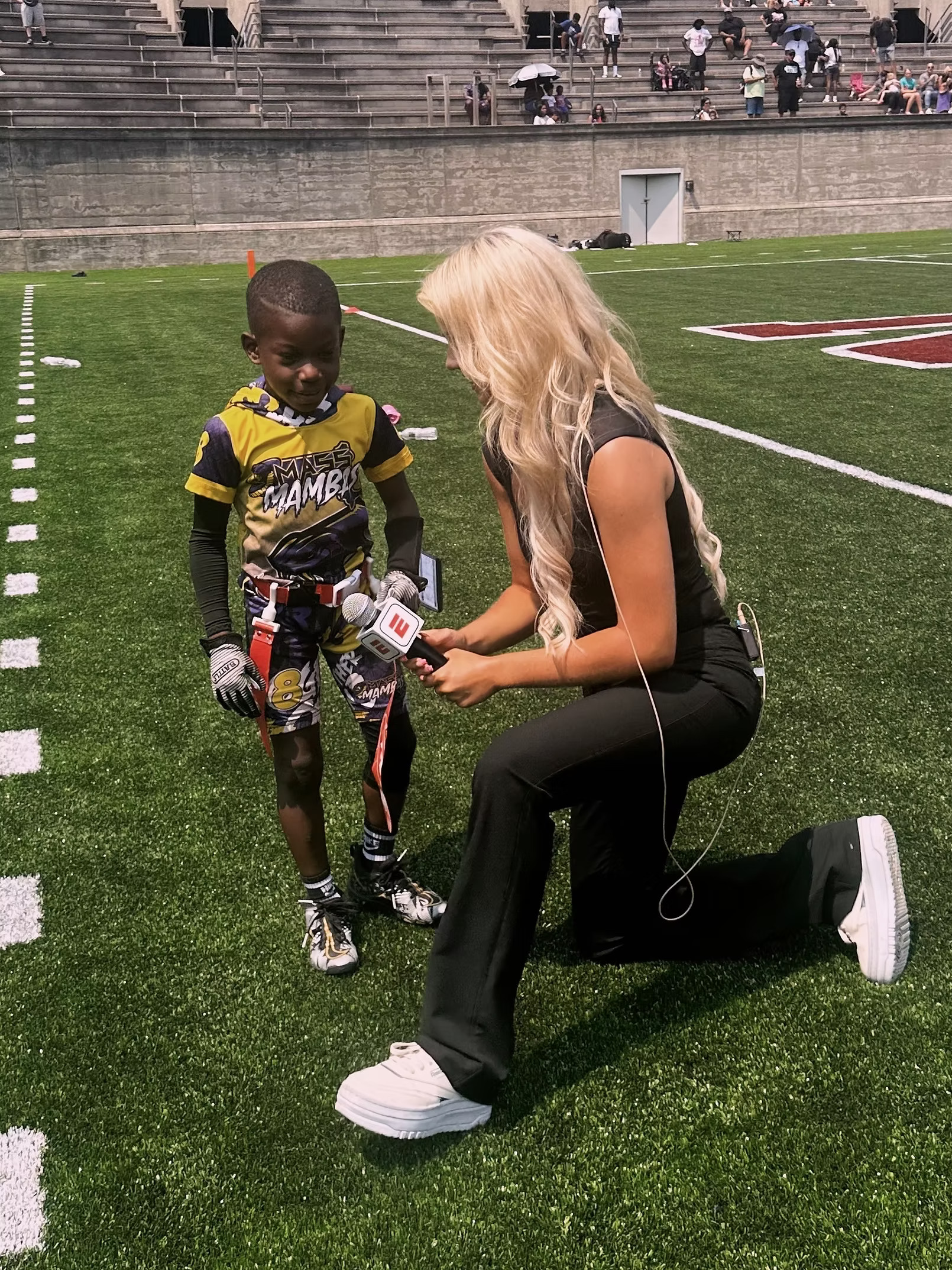 Ava McCoy interviewing a young flag football player at Harvard Stadium