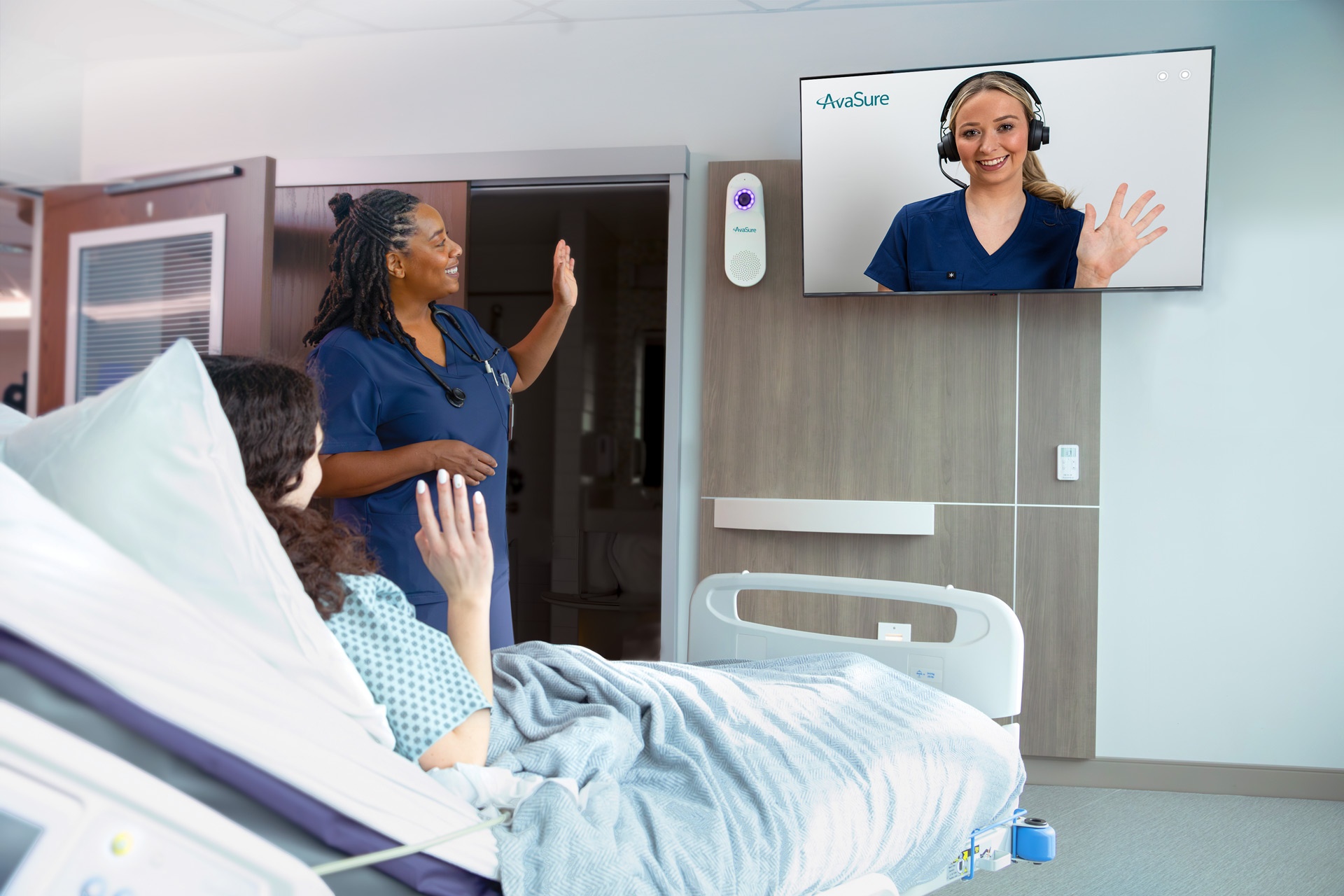 Promotional photograph of a patient and bedside nurse greeting a remote nurse on a room display