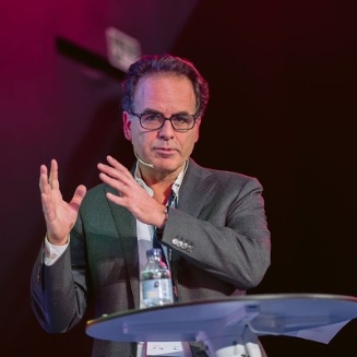 Avi Chai Outmezguine speaking and gesturing behind a lectern