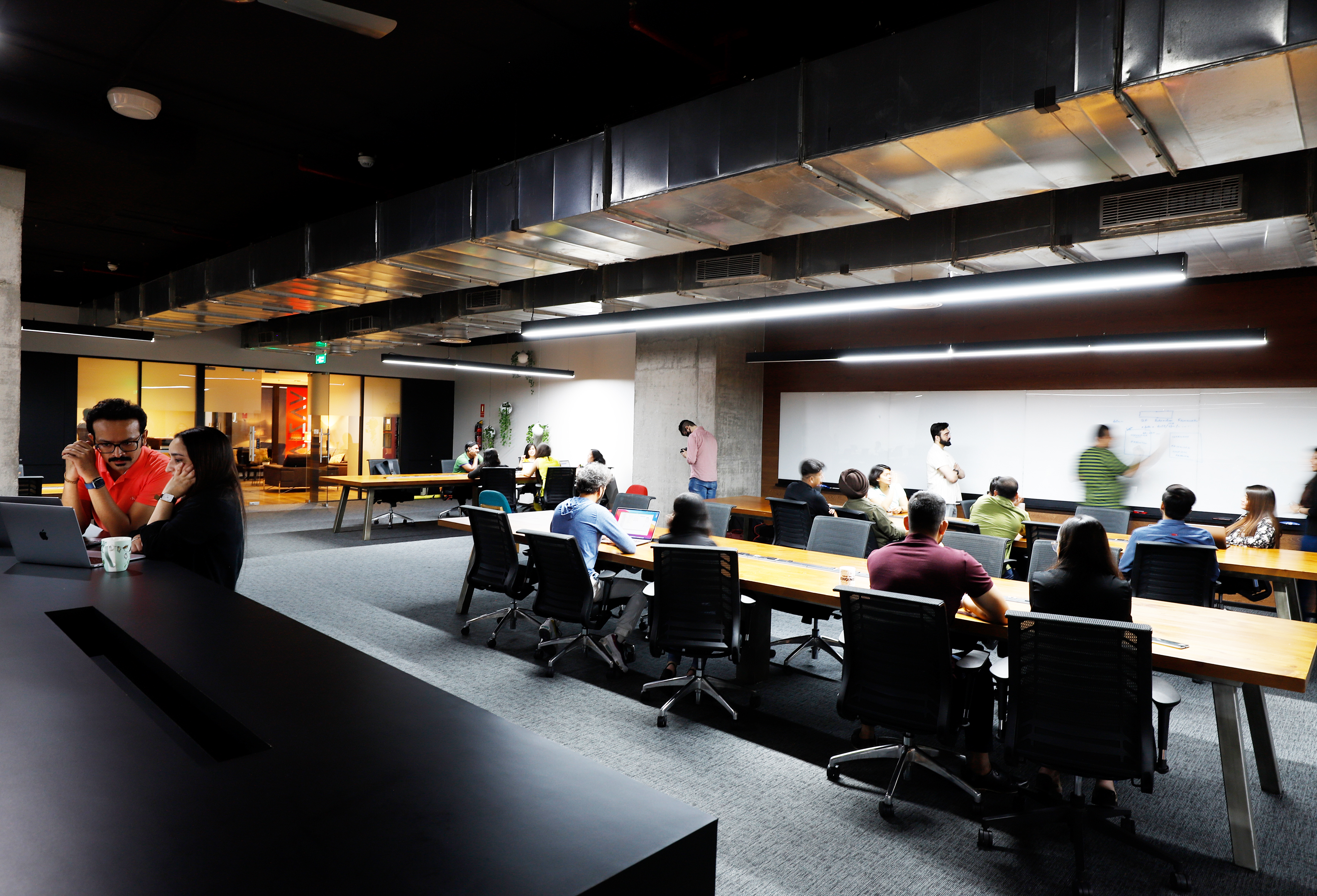 AVIZVA colleagues collaborating at long tables in a shared workspace