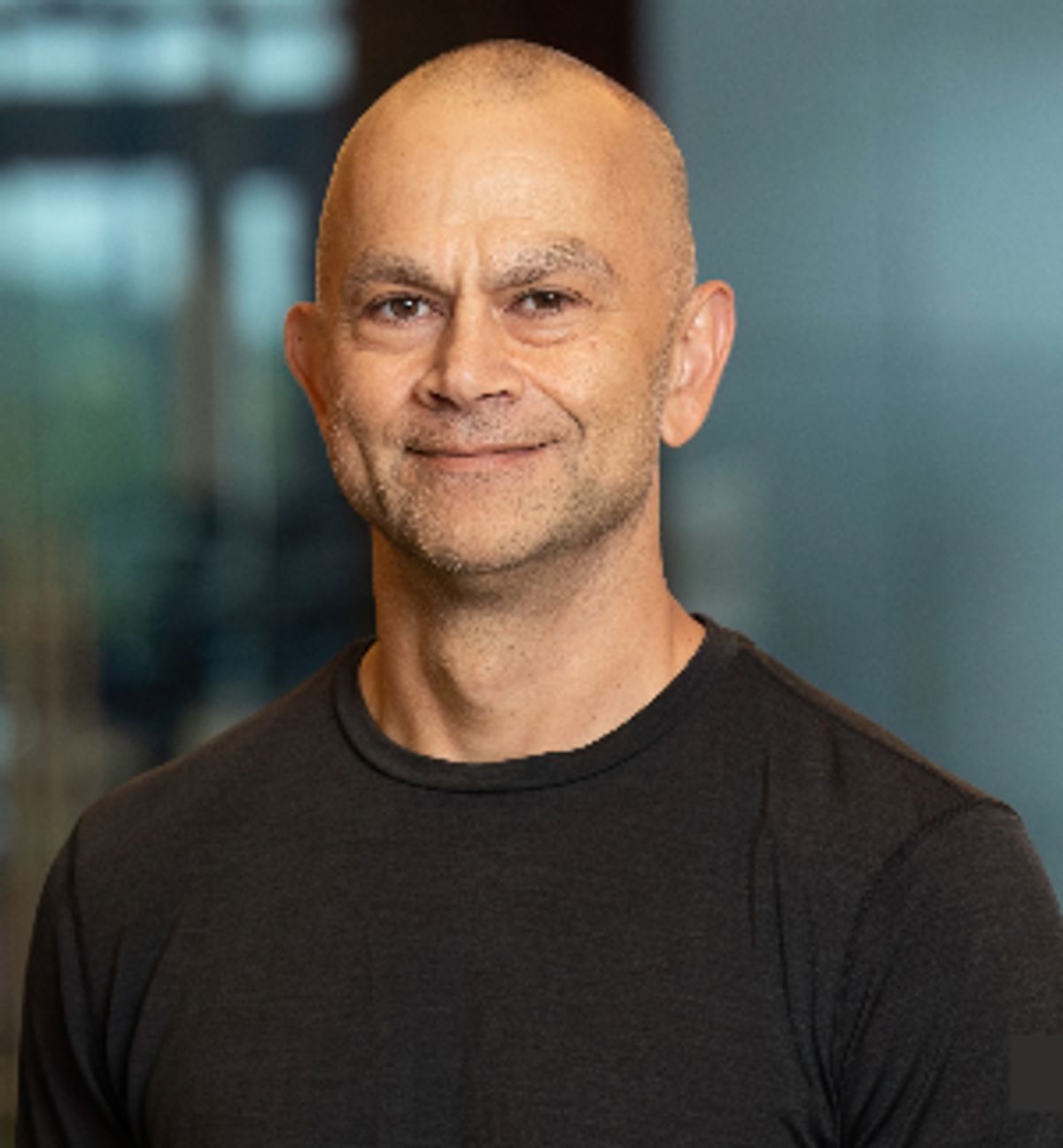 Axel Allgeier in a black shirt, photographed against a softly blurred office background