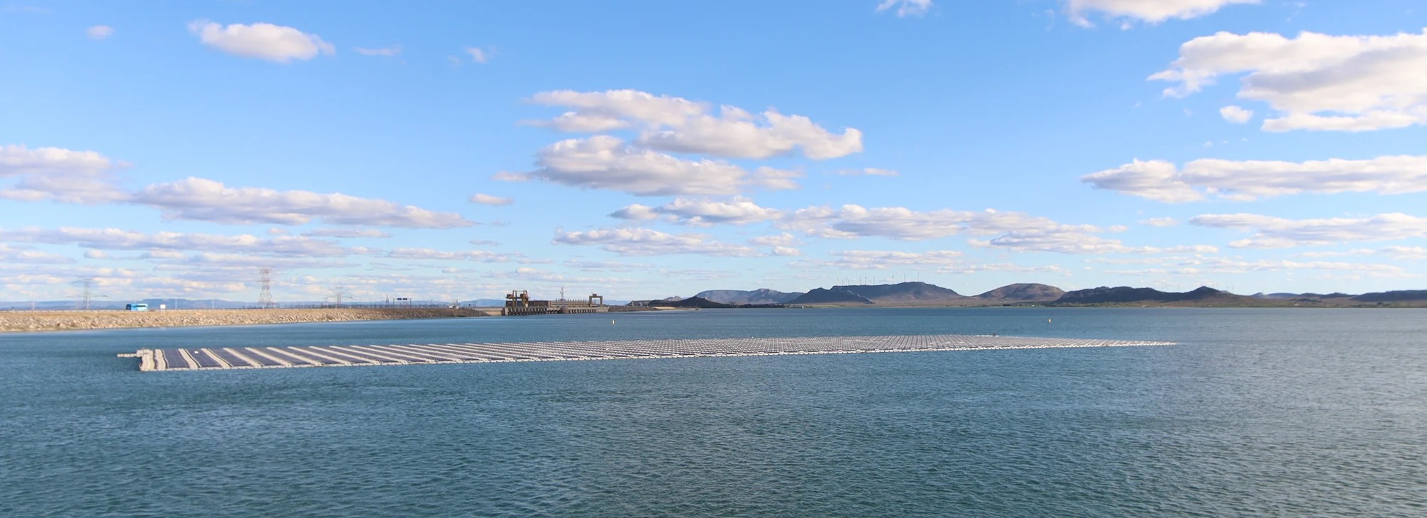 Rows of floating solar panels on a reservoir beneath a blue sky