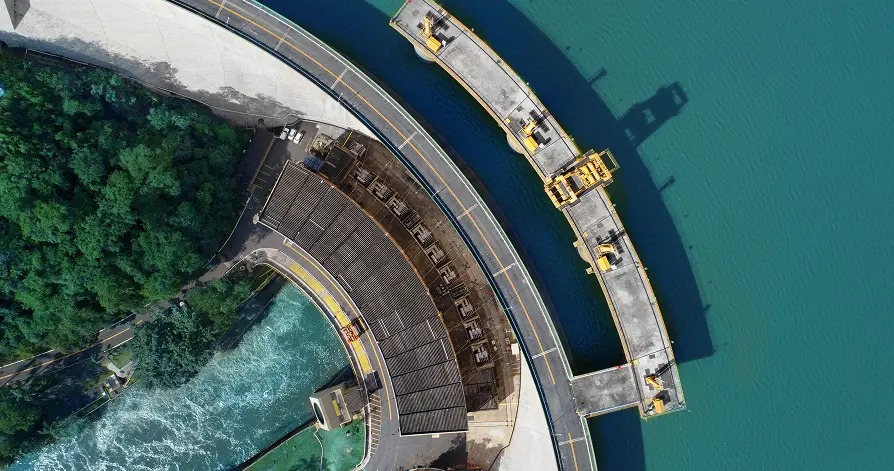 Aerial view of the curved Funil hydroelectric dam, its reservoir, and powerhouse