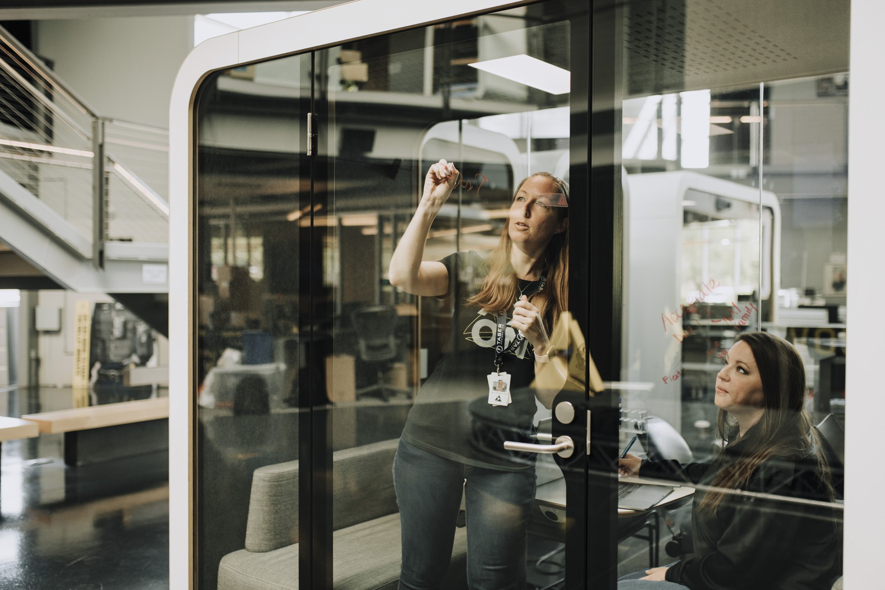 Two Axon colleagues work at a glass writing wall in the Scottsdale office