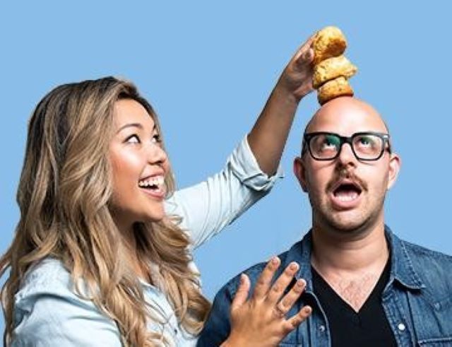 Ayeshah Abuelhiga smiles while balancing three biscuits on Ross Perkins's head