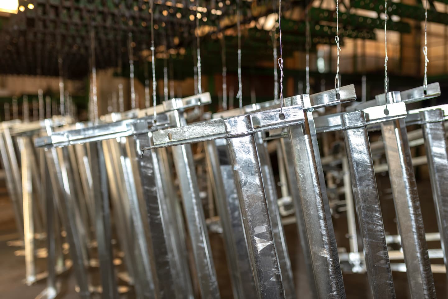 Zinc-coated steel components suspended on wires inside an AZZ plant