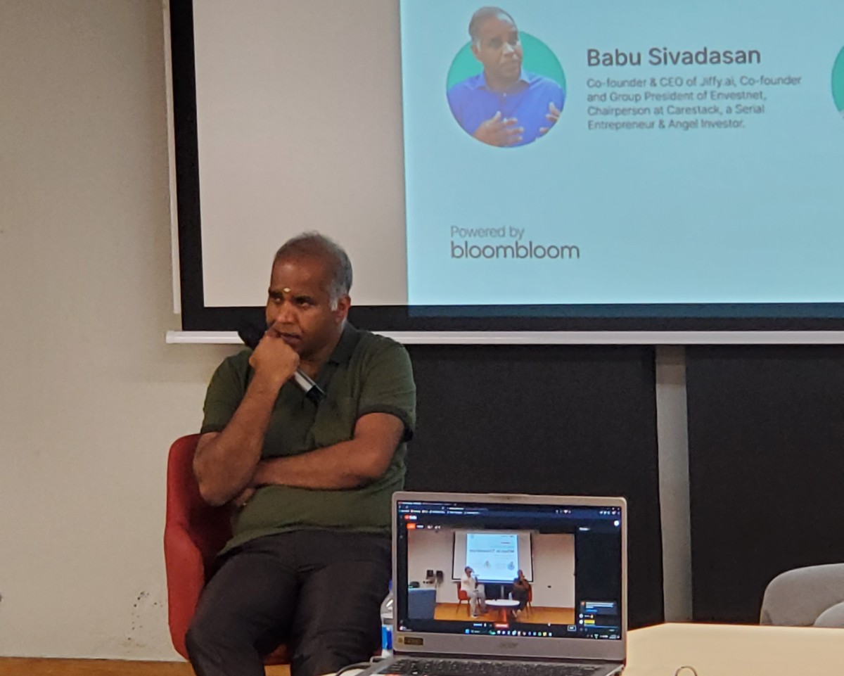 Babu Sivadasan seated with a microphone at a gathering of entrepreneurs in Trivandrum