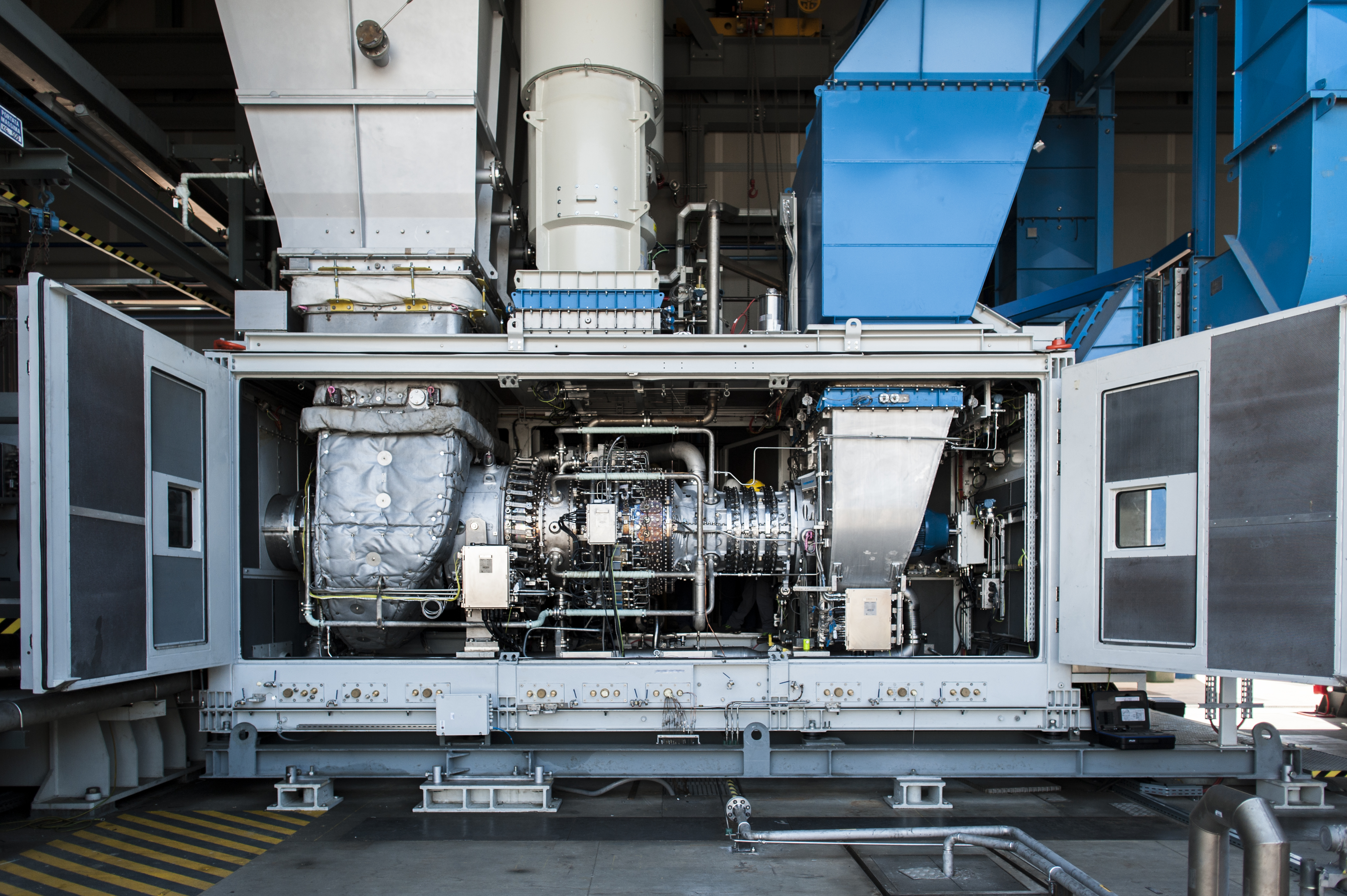 A Baker Hughes NovaLT12 gas turbine with its enclosure doors open, revealing pipework and machinery.