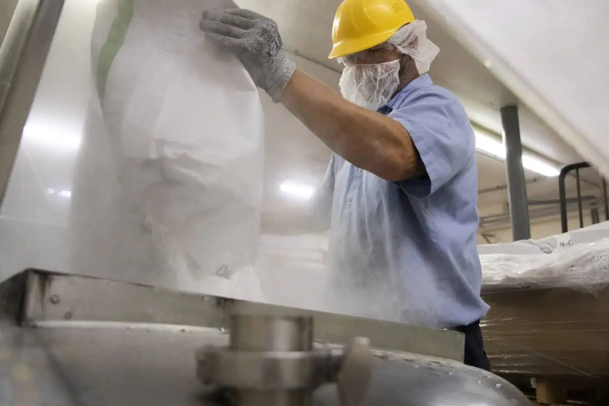 A Balchem employee pours a bag of powder into manufacturing equipment