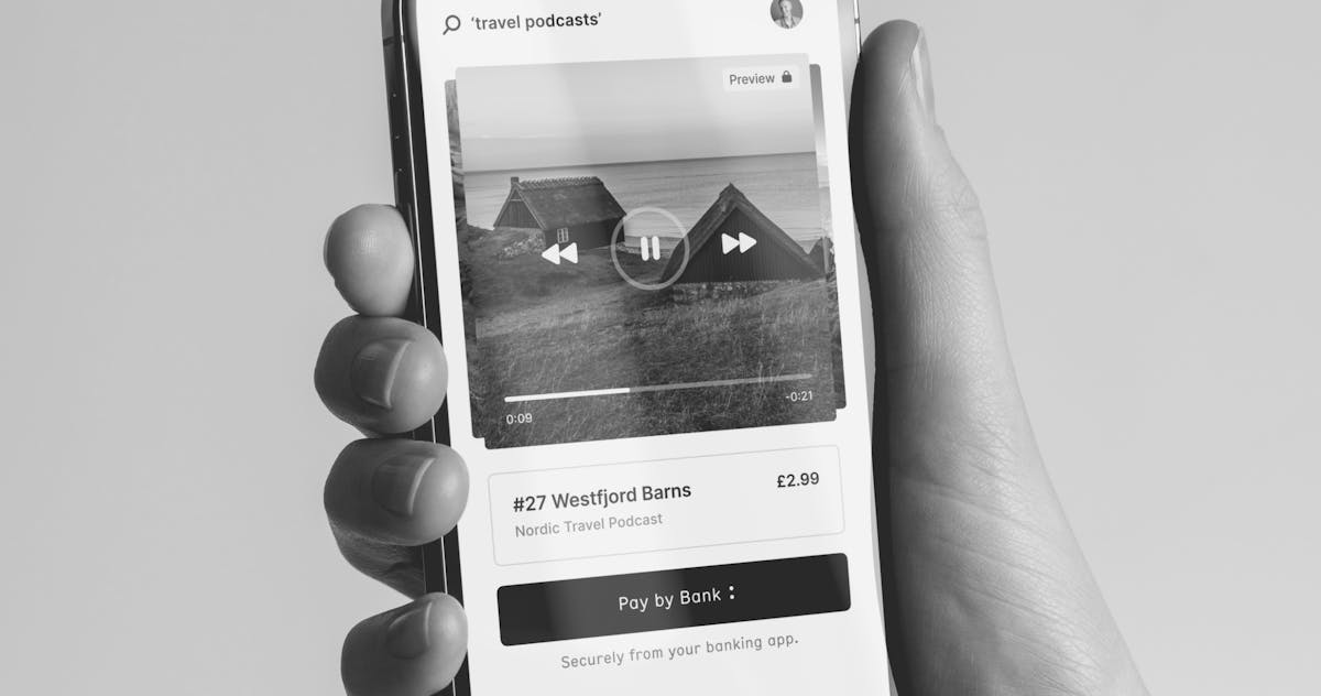 A hand holding a phone showing a Pay by Bank checkout screen