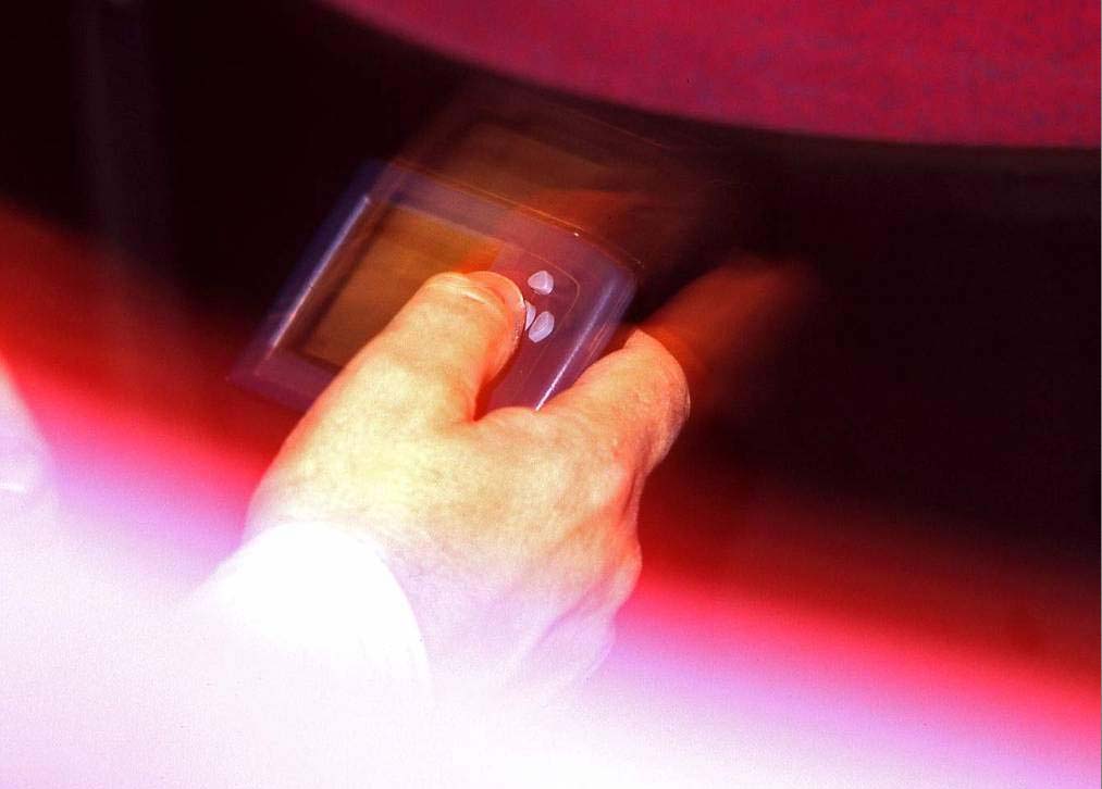 An attendee uses an early SpotMe handheld, photographed in warm red event lighting