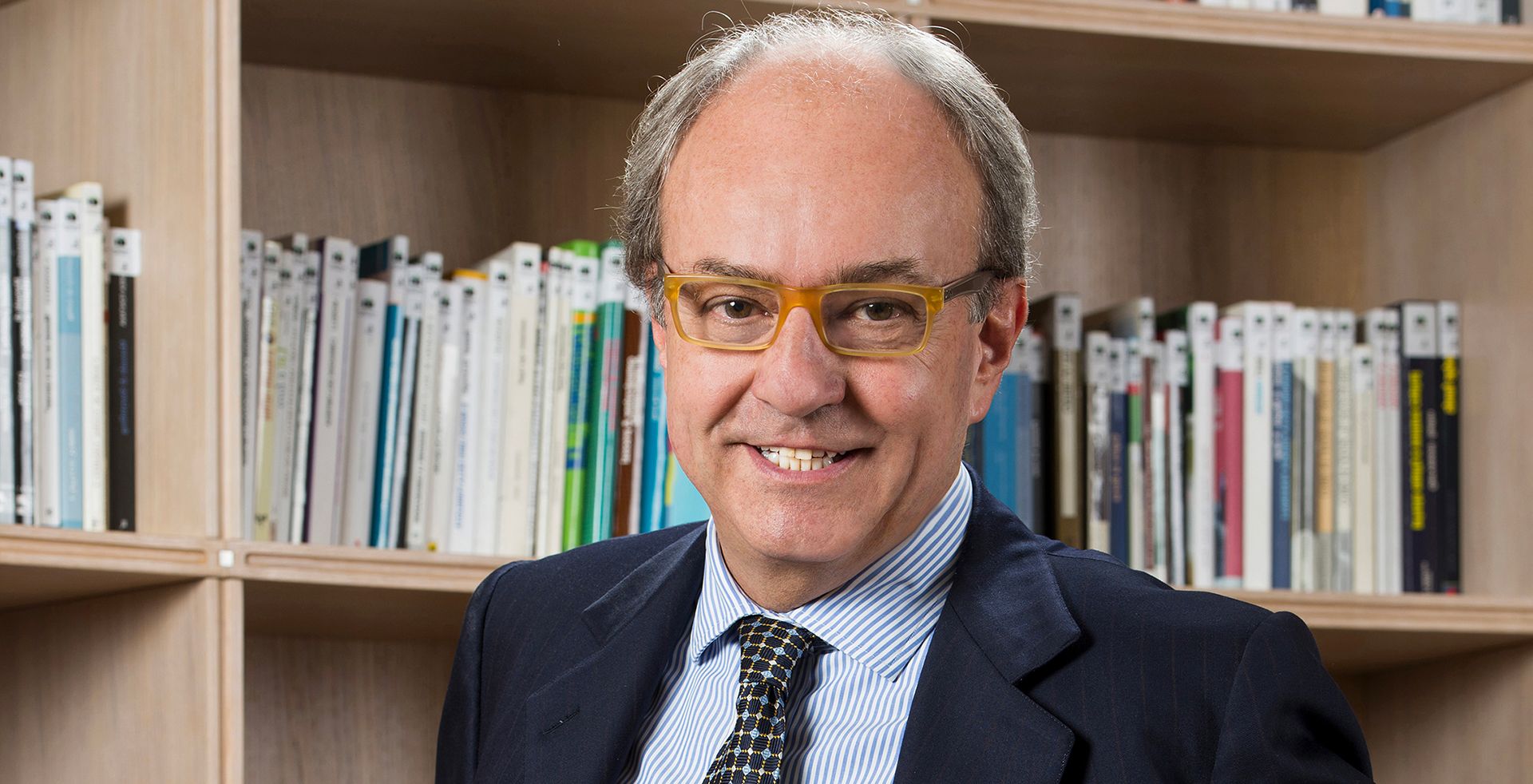 Luca Barabino, founder of Barabino and Partners, seated before a wall of books
