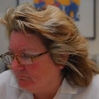 Candid photograph of Barbara Zenz wearing glasses and a white shirt