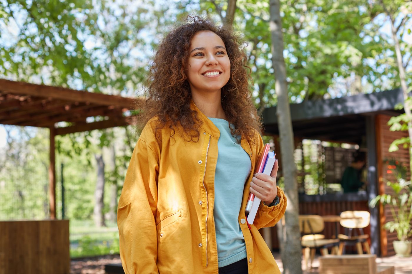 A student holding textbooks outside a campus-style building in a Barnes & Noble College promotional photograph