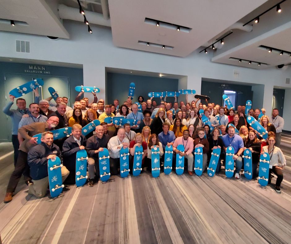 Barrett managers gathered indoors holding blue skateboards