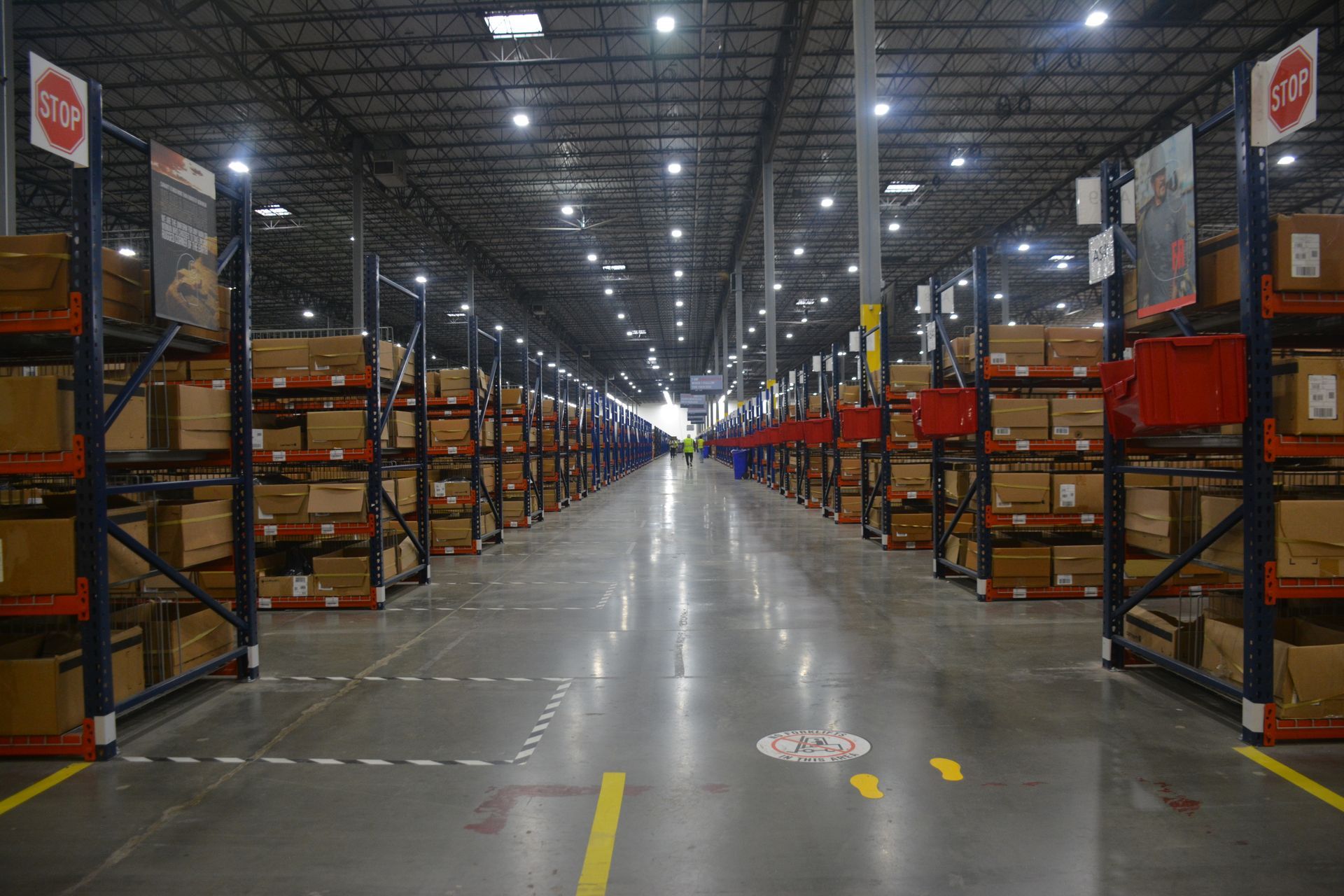 Long warehouse aisle with storage racks, cartons and marked pedestrian lanes