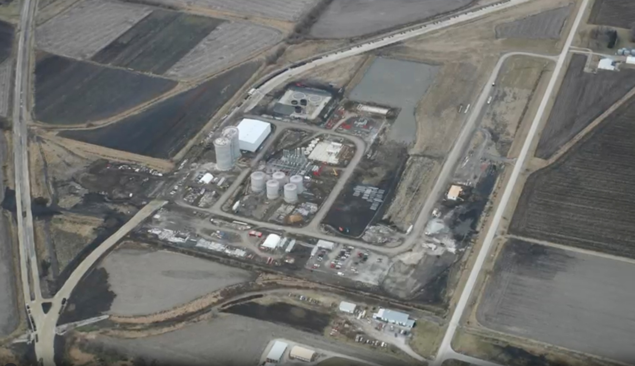 Aerial view of an ethanol plant, with storage tanks, surrounding fields and railway tracks