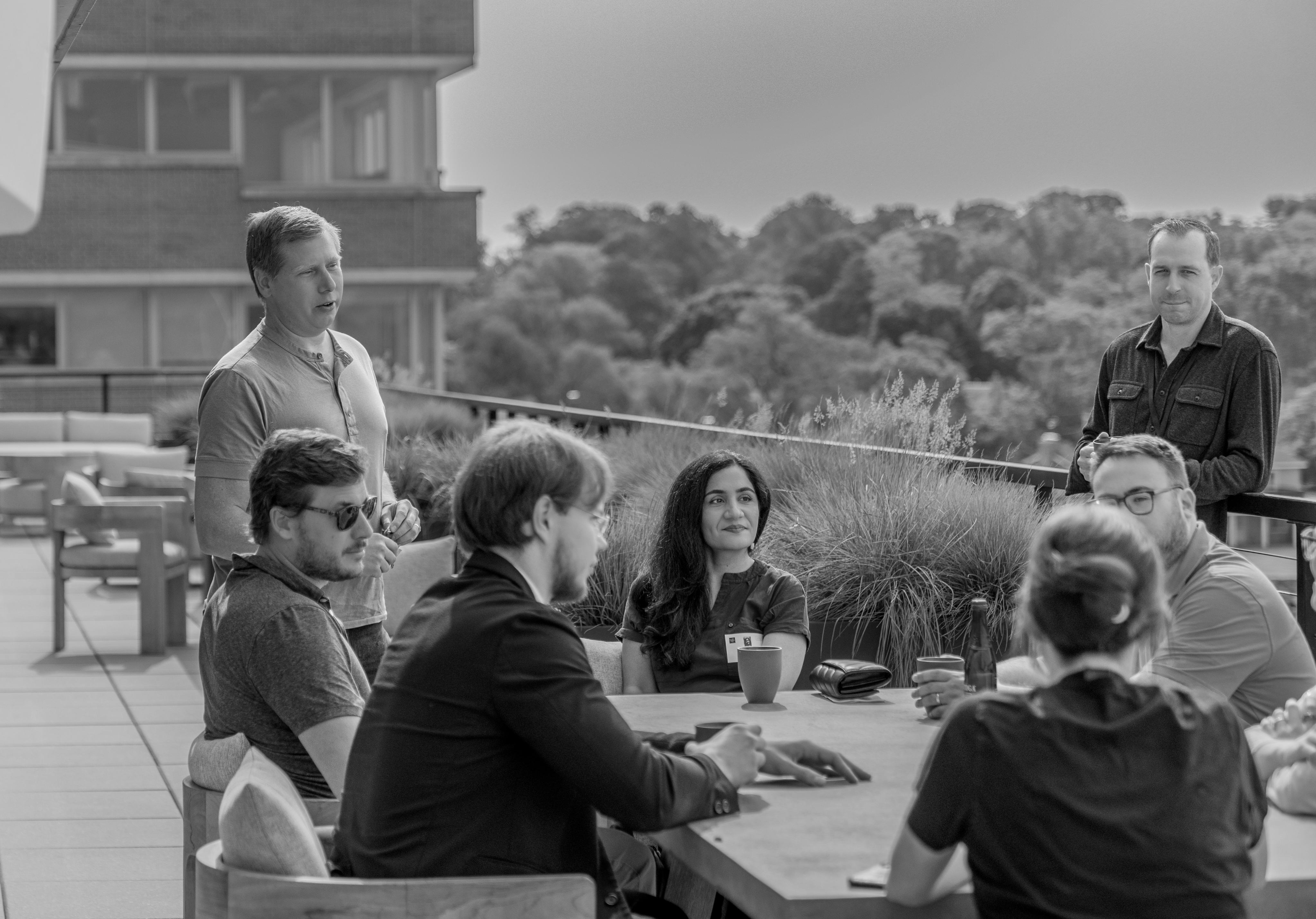 Barry Silbert, standing on the left, talks with BittBridge participants around an outdoor table at Yuma headquarters.