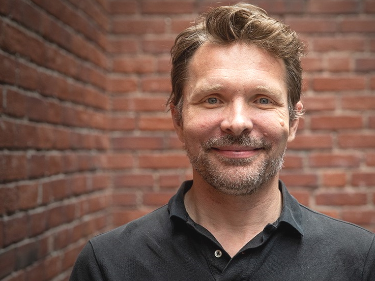 Bart Heilbron in a dark shirt, photographed against a brick wall