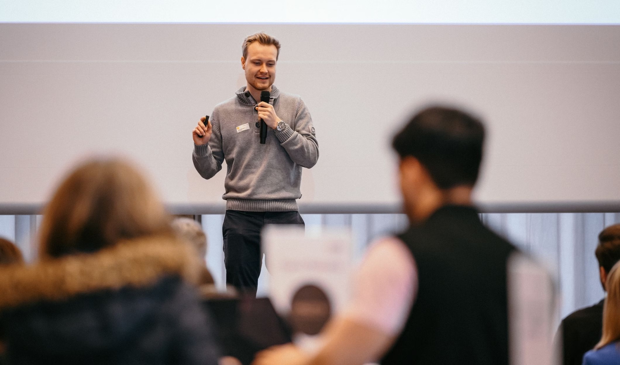 A speaker with a microphone addresses attendees at a 2025 co-founder matchmaking event.