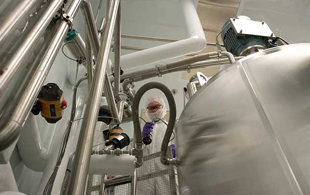 A protected manufacturing worker among stainless steel vessels and pipes at a Bausch Health facility