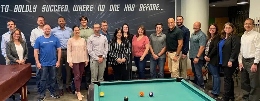 BCM One team members gathered around a pool table in an office
