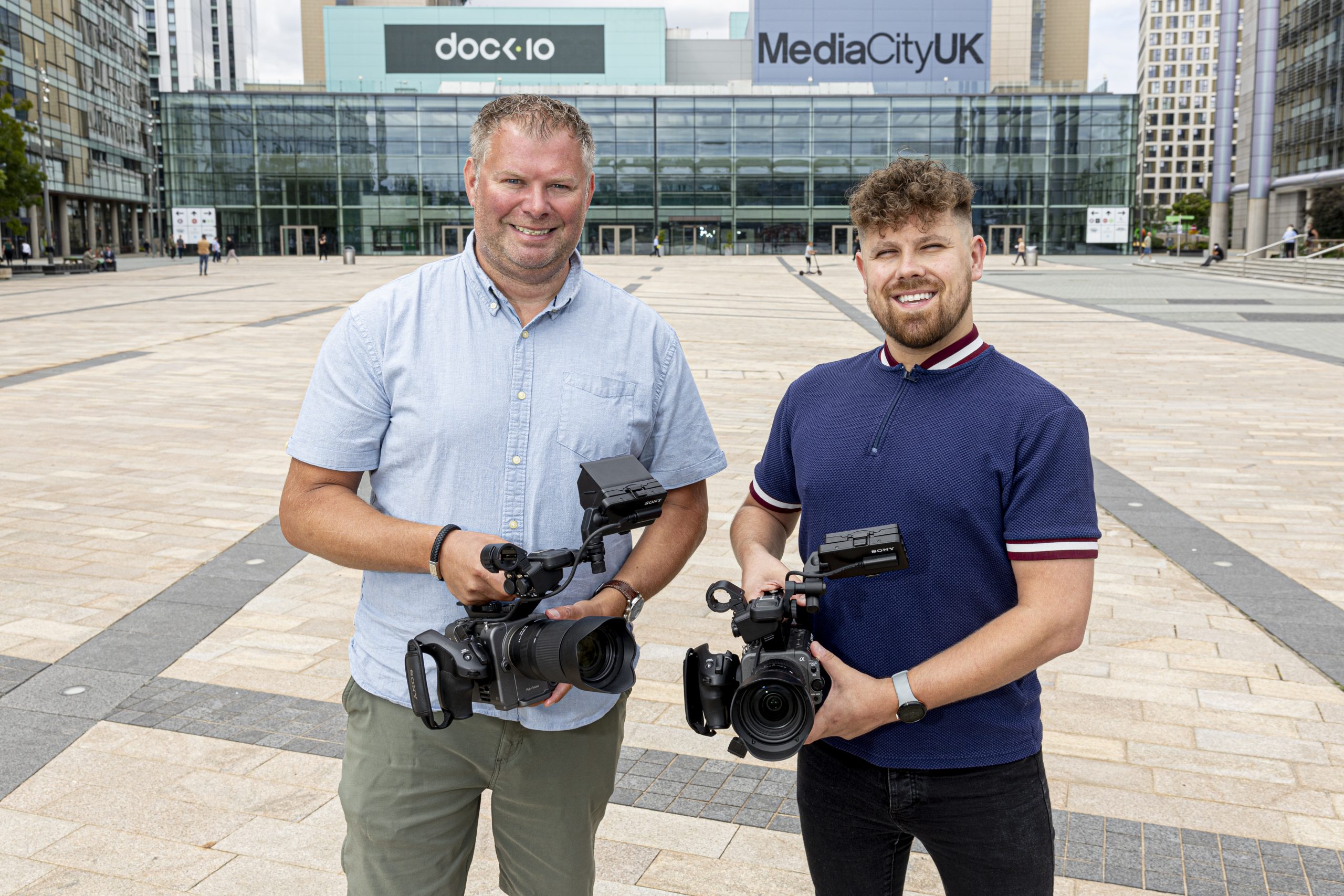 Two AV Room camera operators holding professional video cameras outside MediaCityUK