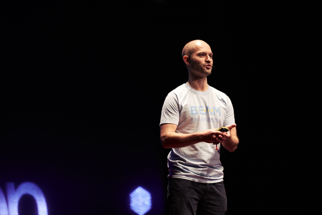 Beam co-founder Alex Stephany speaking onstage, holding a presentation remote