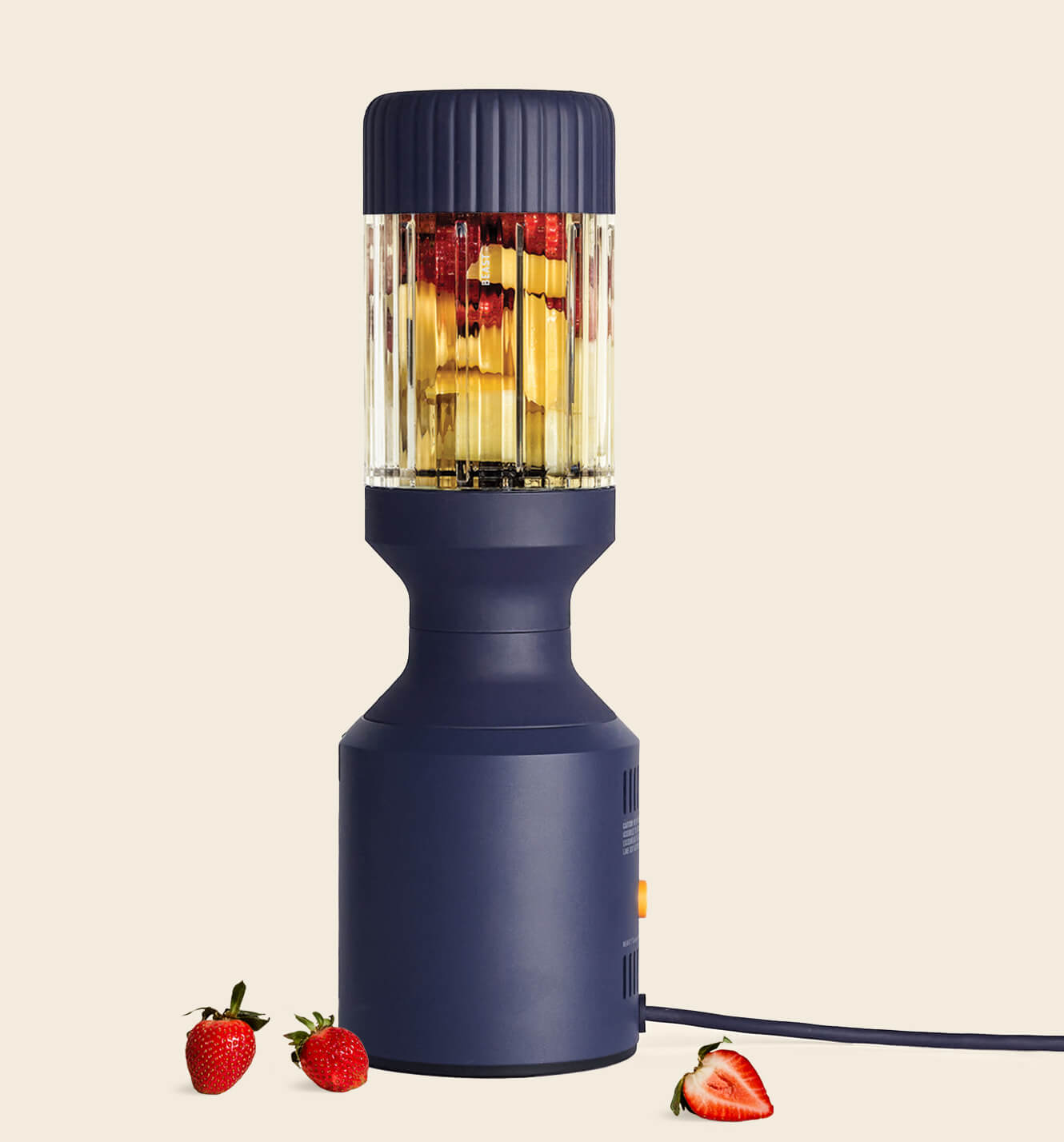 A navy Beast Mega blender filled with strawberries on a warm cream background