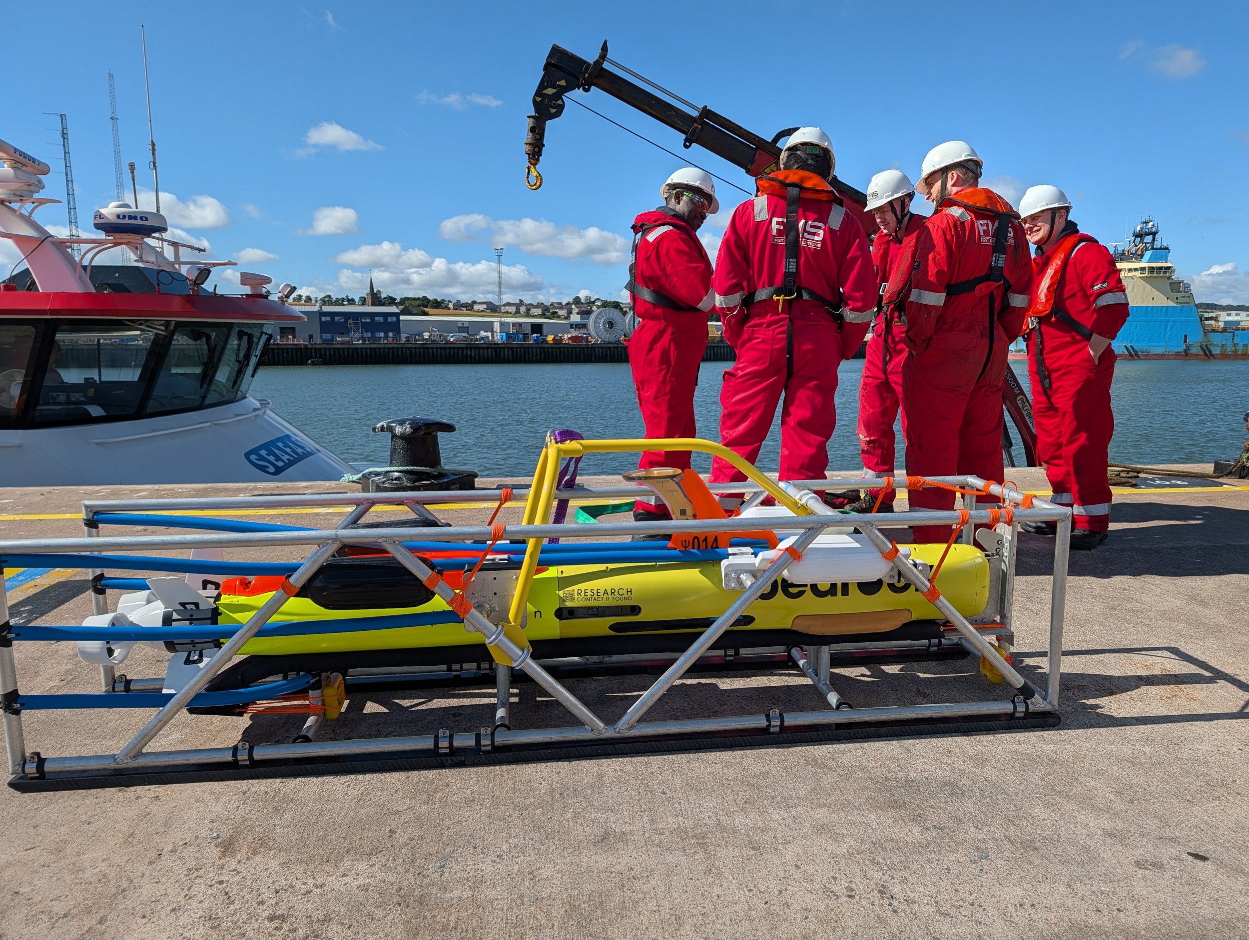 First Marine Solutions survey crew beside a Bedrock autonomous underwater vehicle at a harbor