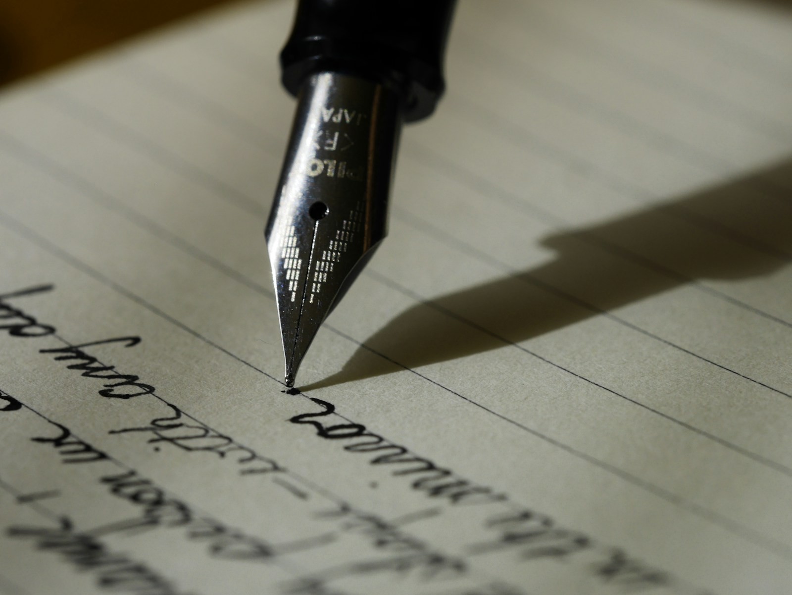A fountain pen touching a lined page