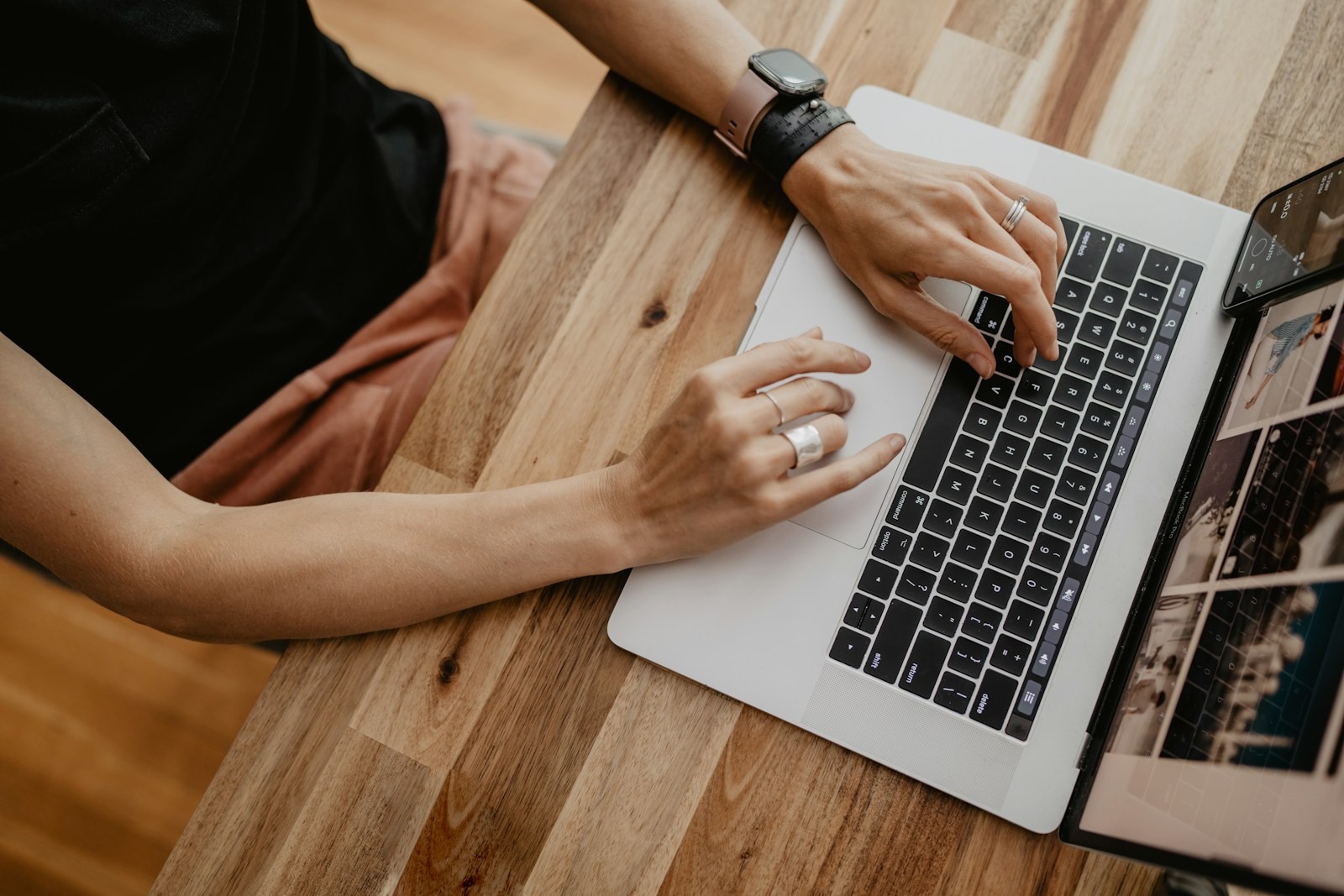Hands typing on a laptop at a wooden desk