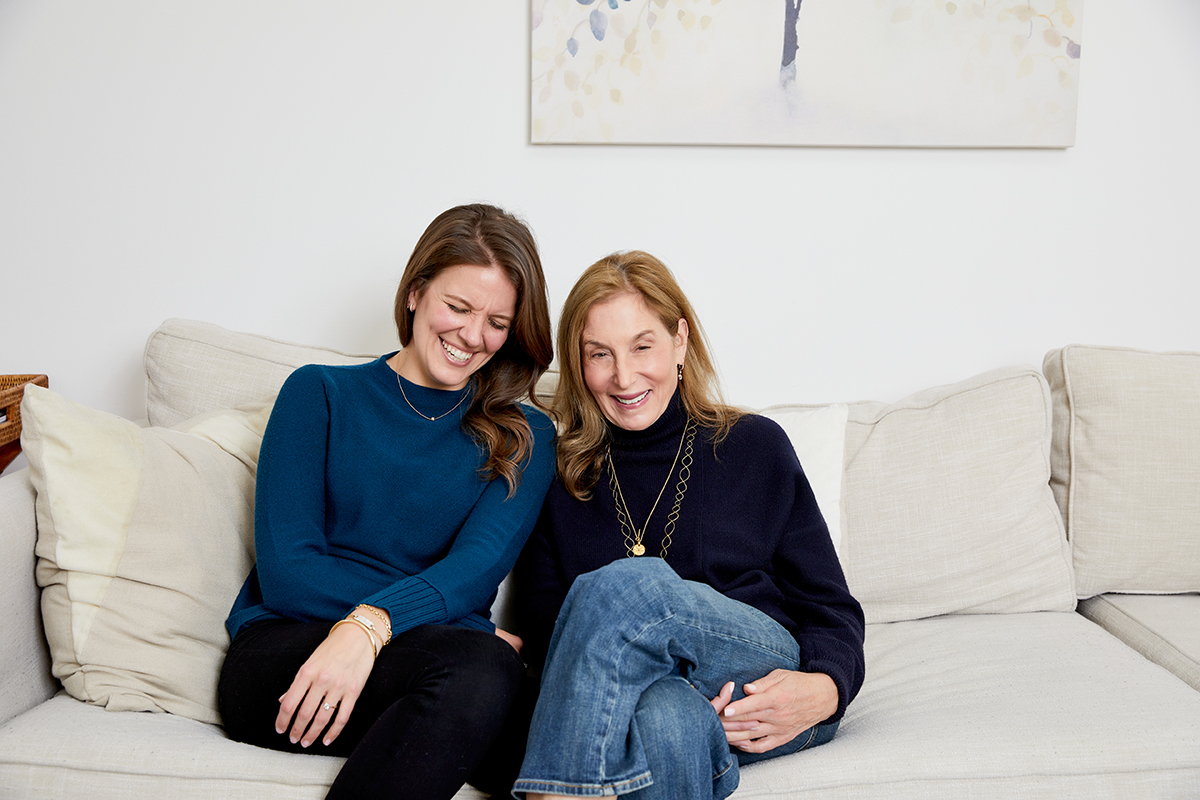 Gianna Cesa and Nancy Behrman laughing together on a sofa