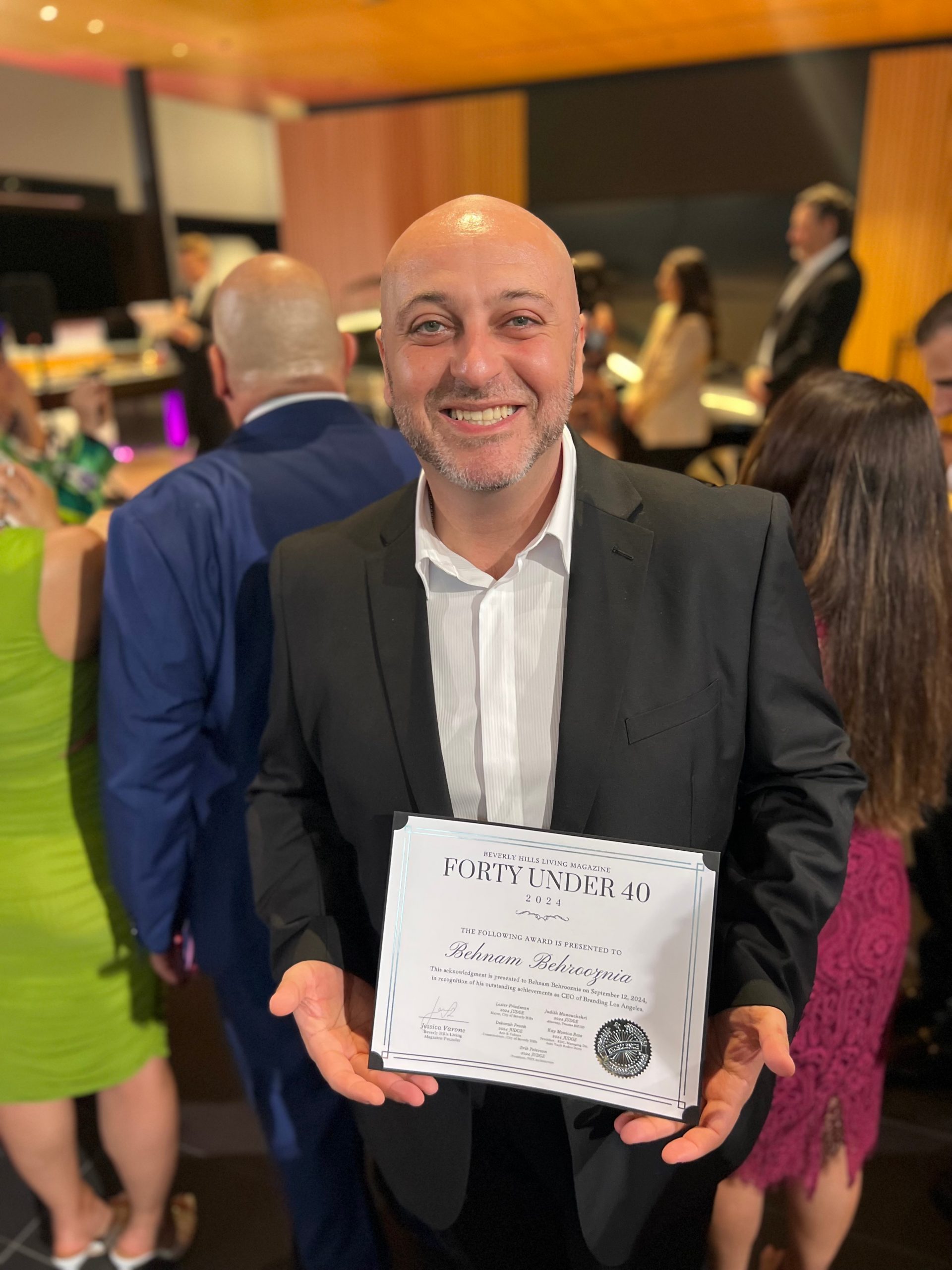 Ben Behrooz holds his Beverly Hills Living 2024 Forty Under 40 certificate at an event.