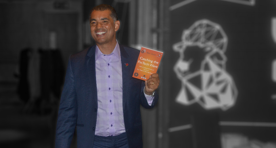 Ben Goss holding an orange copy of Catching the FinTech Wave