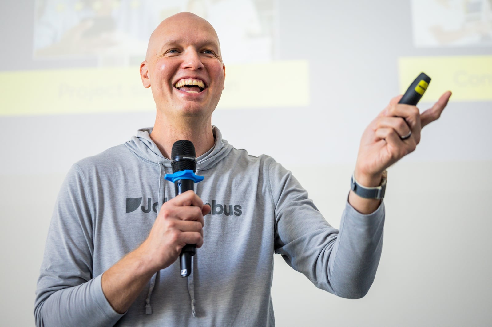 Ben Hodson holding a microphone and presentation remote while speaking to his sales team at JobNimbus