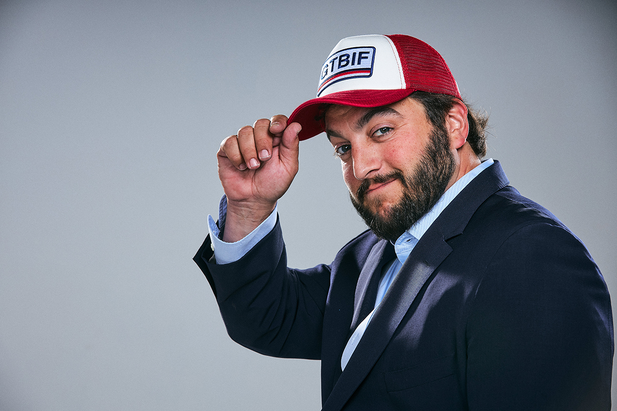 Ben Kovler tipping a red and white GTBIF cap while wearing a navy jacket