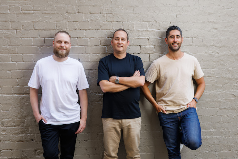 FoodByUs co-founders Tim Chandler, Gary Munitz and Ben Lipschitz standing together against a brick wall