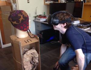 Ben Mildenhall trying a headset beside a mannequin on a cardboard box