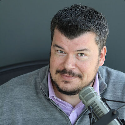 Ben Newton seated at a microphone during an interview