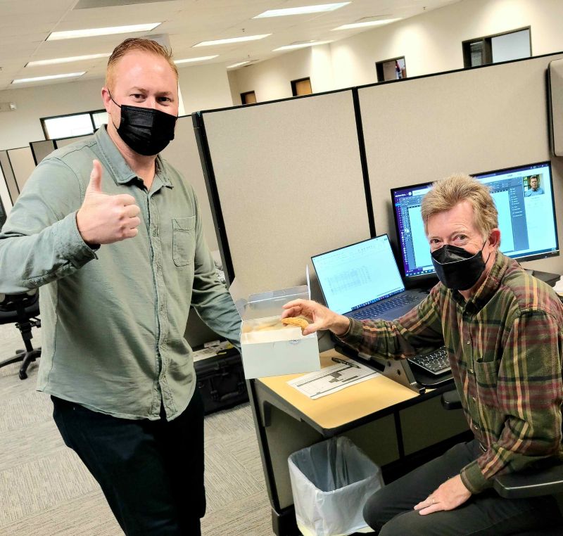 Ben Schuler gives a thumbs-up while sharing cookies with a colleague at the Infinitum office