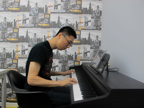 Ben Ye seated at a digital piano, playing during his 2015 interview