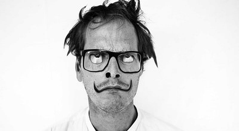 Benji Vaughan in a playful archival black-and-white press photograph with a curled moustache