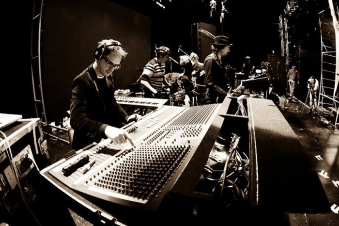An archival Younger Brother photograph showing musicians working around a large mixing console