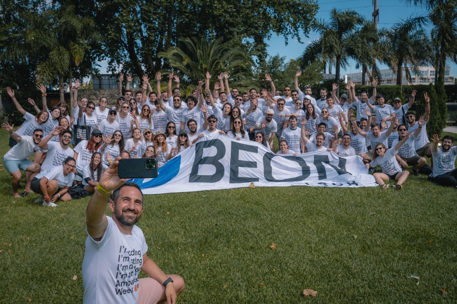 BEON colleagues gather outdoors for a company day, with a group selfie in progress