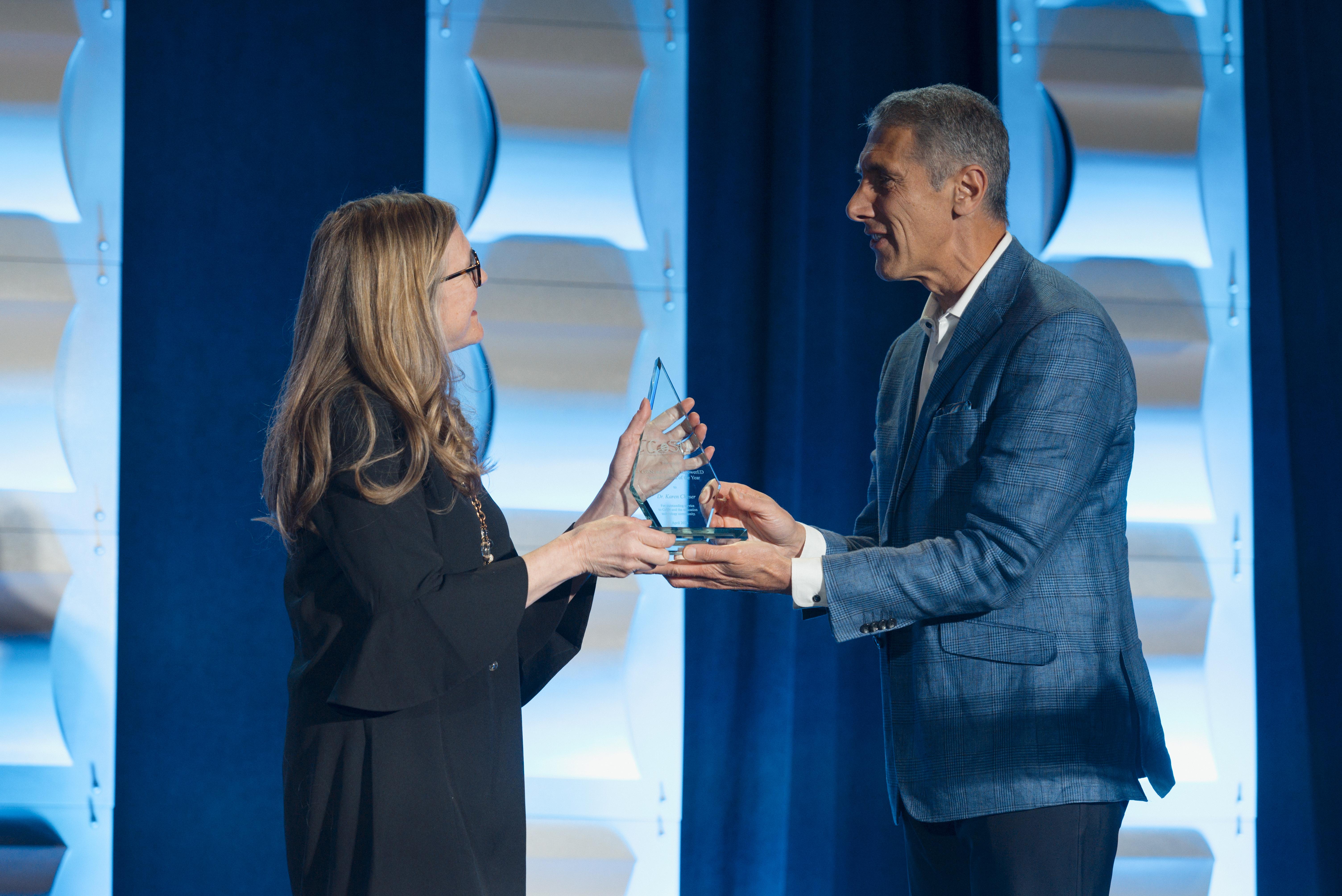 Berj Akian presents a glass award to Durango superintendent Karen Cheser at CoSN’s 2025 conference