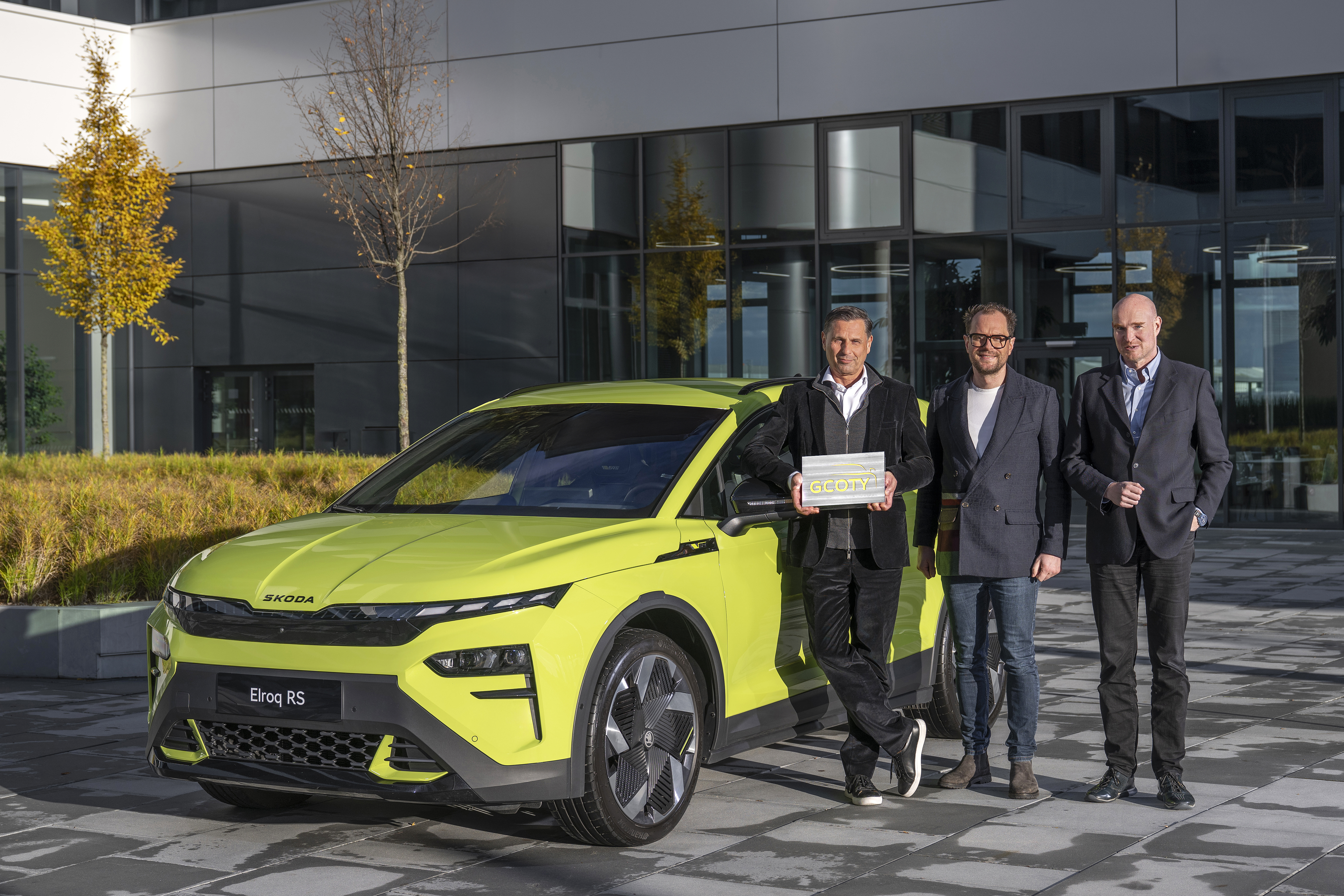 Klaus Zellmer, Bernd Hitzemann and Jens Meiners holding the German Car of the Year award in front of a Škoda Elroq