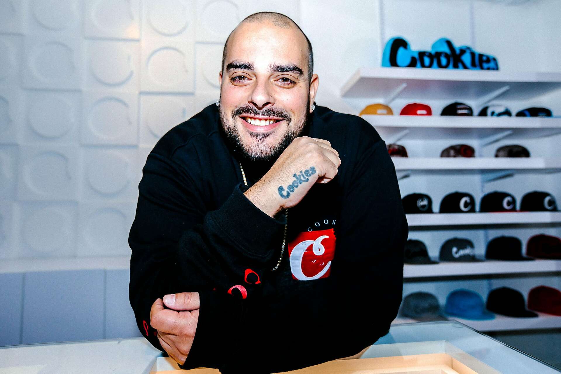 Berner smiling behind a retail counter with Cookies hats on the shelves